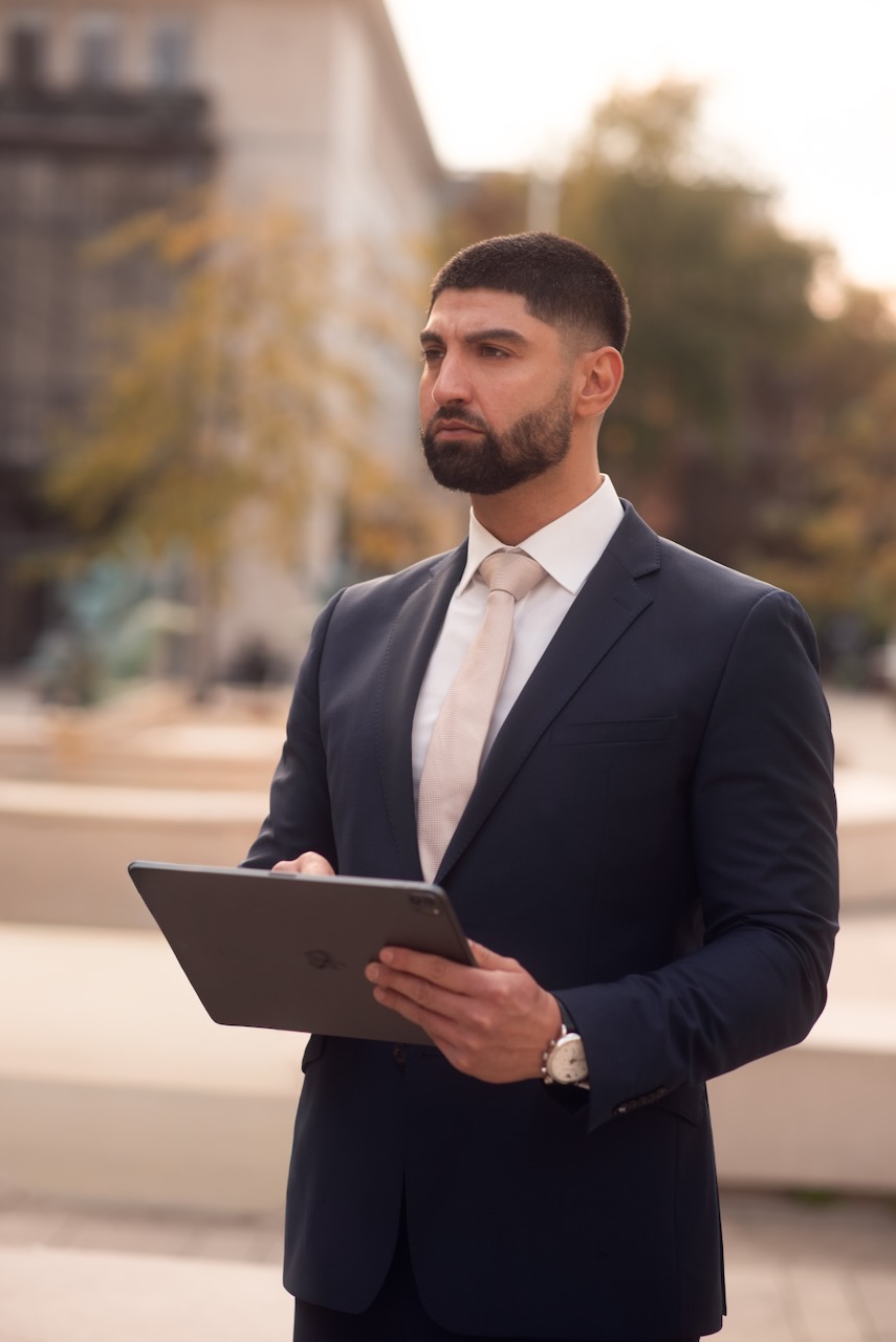 Businessporträt eines Mannes im dunklen Anzug vor einer modernen Fassade