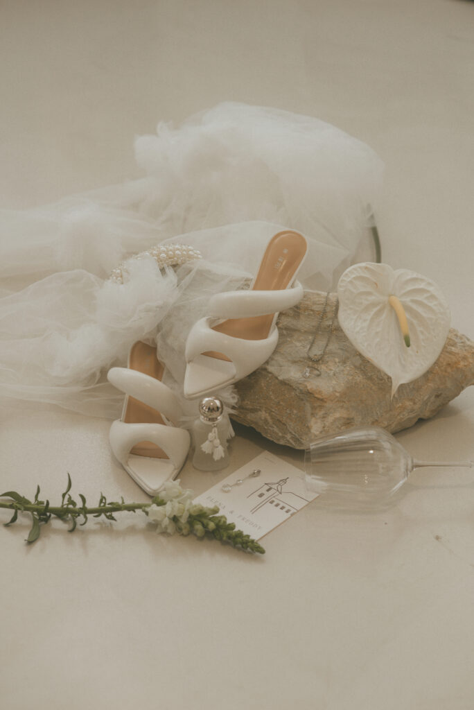 Weiße Brautschuhe, Schmuck und eine weiße Blüte als Hochzeitsdetails